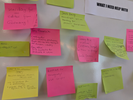 White wall with colorful post-its answering the printed question of "What I Need Help With"