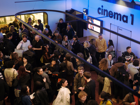 Shot from above of a crowded lobby with a sign that reads Cinema 1 visible in the background