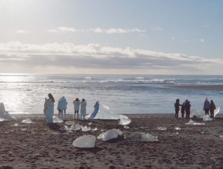 Far away shot of people on a desolate beach admiring the melting chunks of ice at an arctic beach