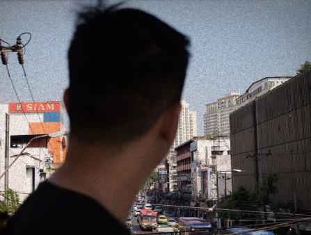 The back of a man's head dominates the frame as he looks on at a crowded street
