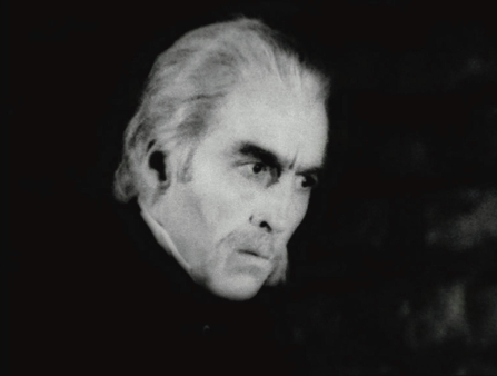 Black and white close-up of a white-haired white man with bushy eyebrows and mustache frowning