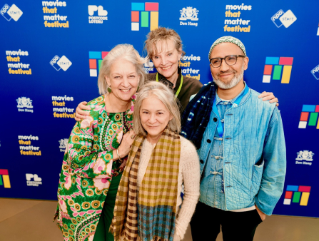 Four people dressed nicely but colorfully stand in front of a blue background with the text "movies that matter festival" and a logo of colorful rectangles. There are three women and one man