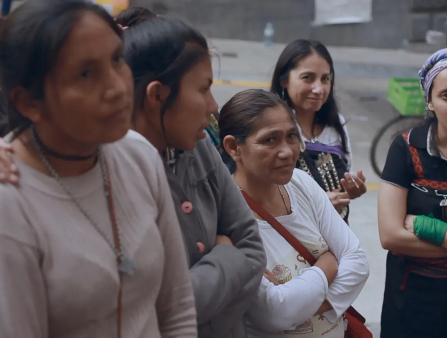A group of six women of various ages look at someone behind the camera. The three on the right faintly smile.