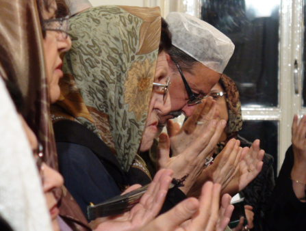 Close shot from the side of a row of people holding out hands in prayer