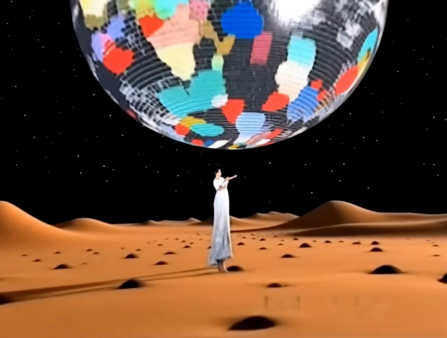 A rendering of a woman in a long white dress standing amid an orange landscape of dunes in front of a black background. An enormous disco ball floats above her head, with splotches of color reflected