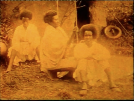 Orange image of three people wearing white robes sitting in the dirt