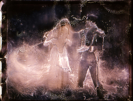 Heavily distorted image of a man in a soldiers uniform comforting a woman who has been replaced with light and looks down at her feet. The background of the image is solid black
