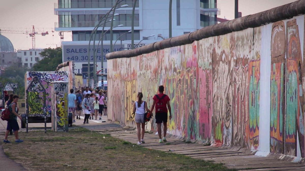 A young couple walks along a preserved segment of the Berlin Wall in 2014