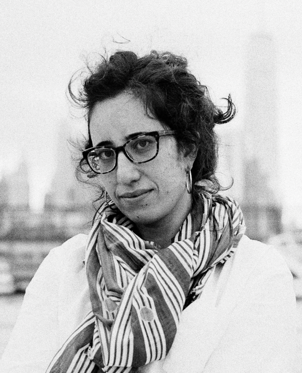 Black and white photo of a white woman with dark hair wearing glasses and a patterned scarf