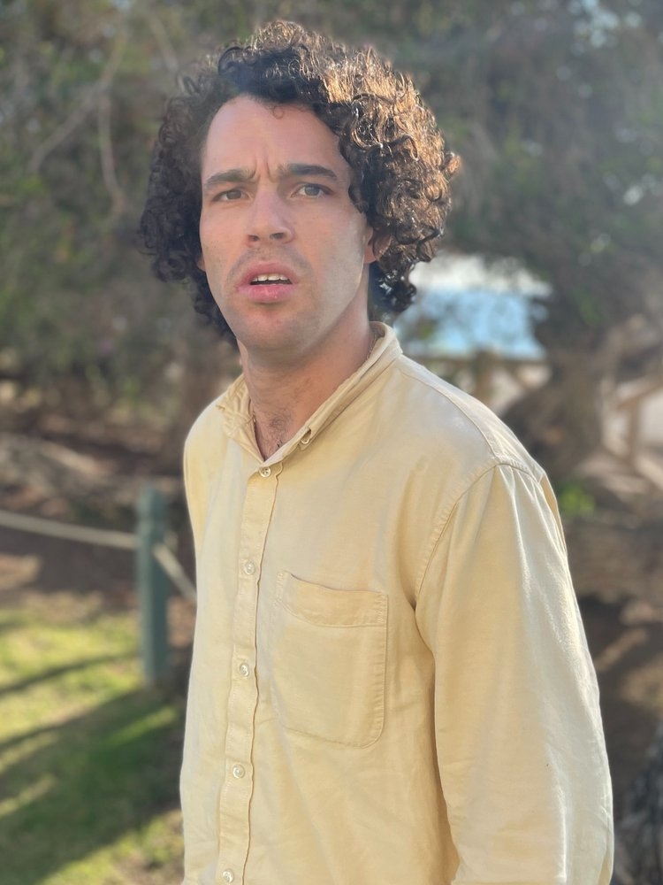 headshot of director Reid Davenport wearing a yellow shirt