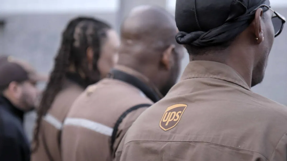 Photo of several UPS workers at an organizing event facing away in their brown uniforms.