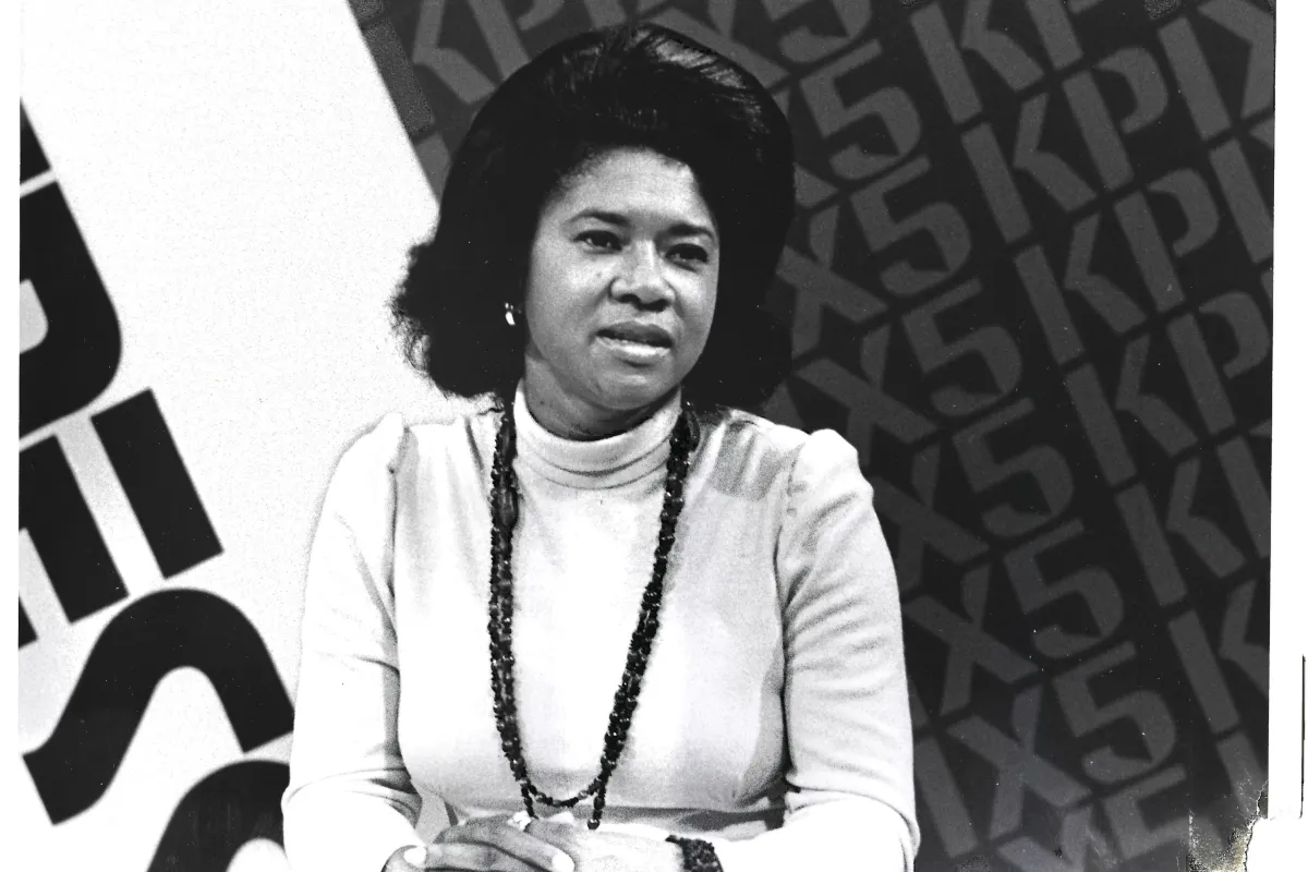 A black and white photograph of a woman with dark hair wearing a white top.