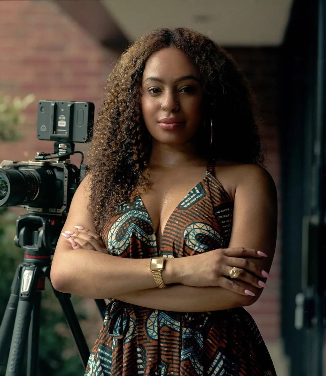 Headshot of Alahna Lark posing next to a camera