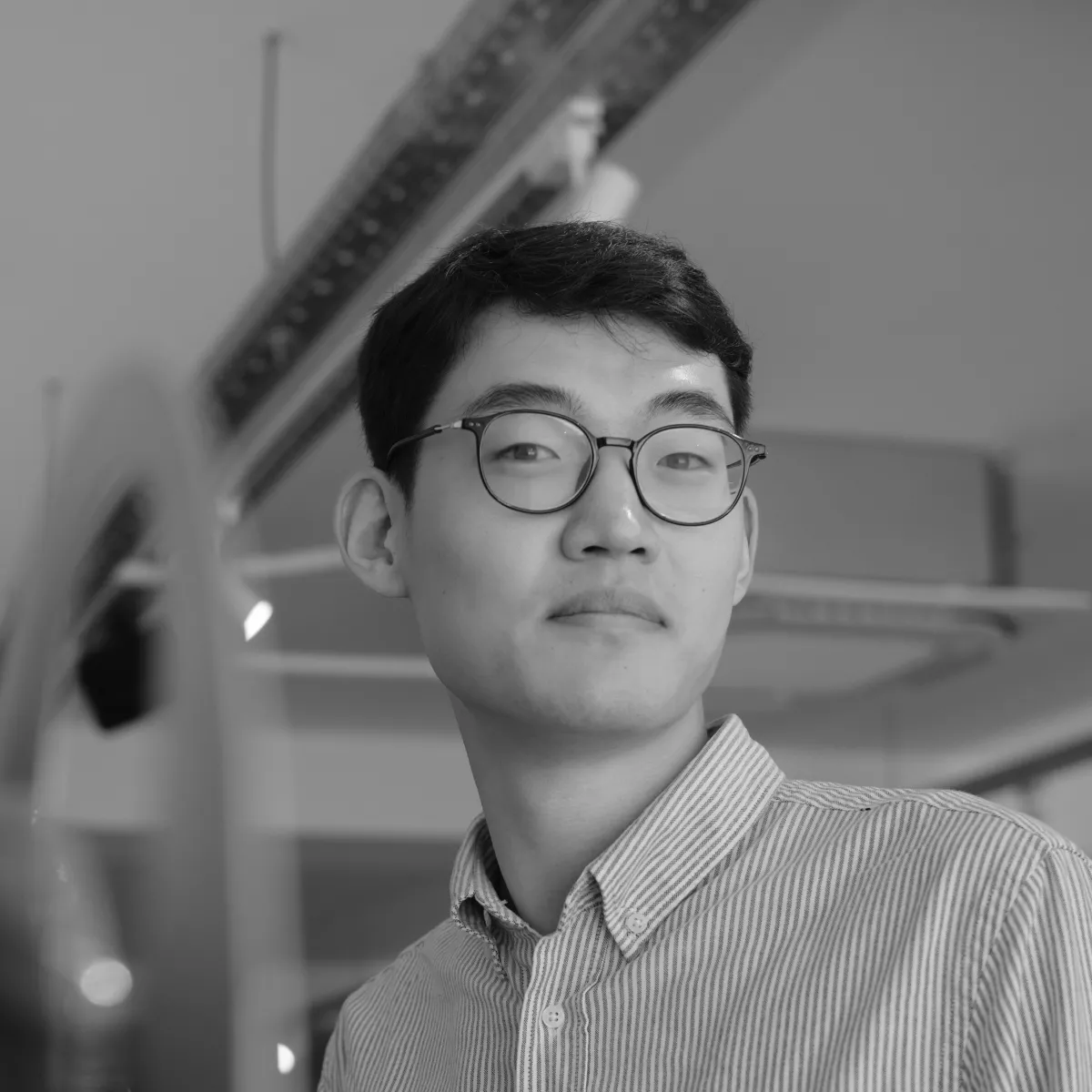 An Asian male with glasses stares at the camera.