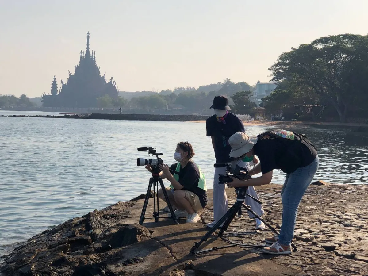 Three women set up cameras besides the water.
