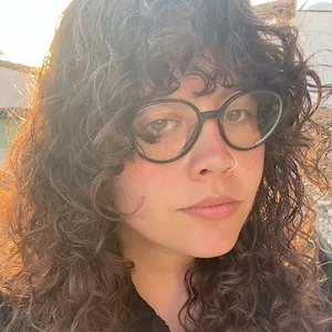 Headshot of a woman with glasses and curly brown hair.