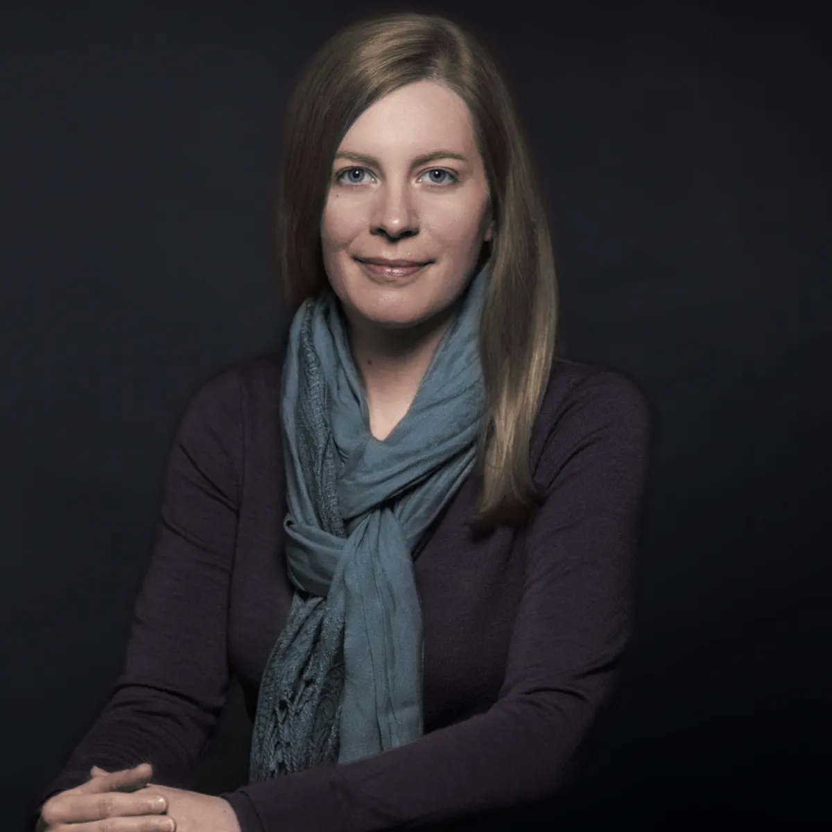 Headshot of a smiling white woman with shoulder length hair wearing a sweater and scarf.