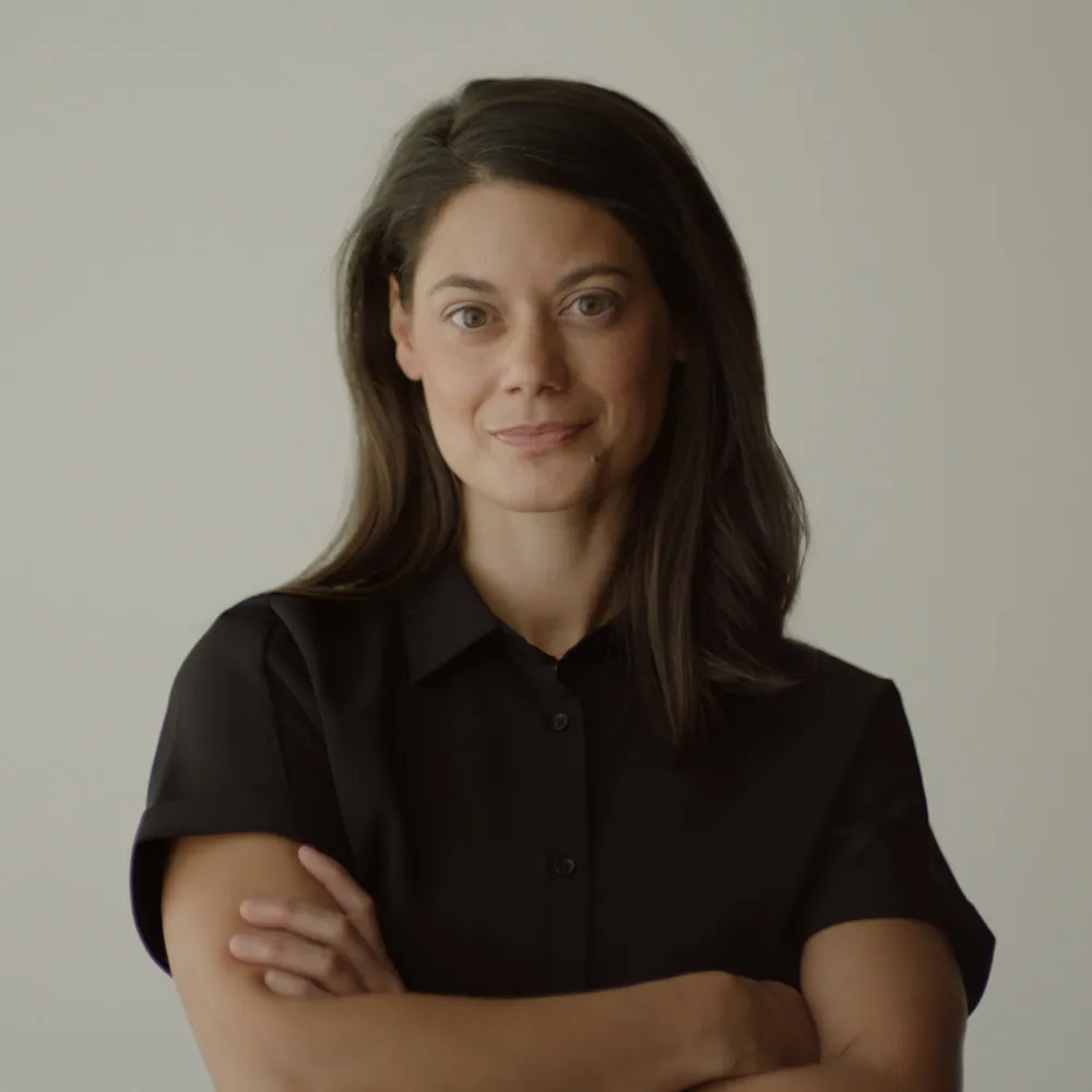 Headshot of a female with olive skin and medium-length brown hair in a black shirt