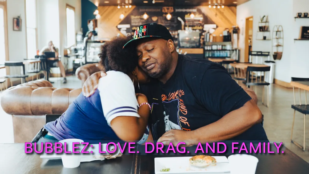 Bubblez and his teenage daughter hug while sitting at a table at a coffee shop.
