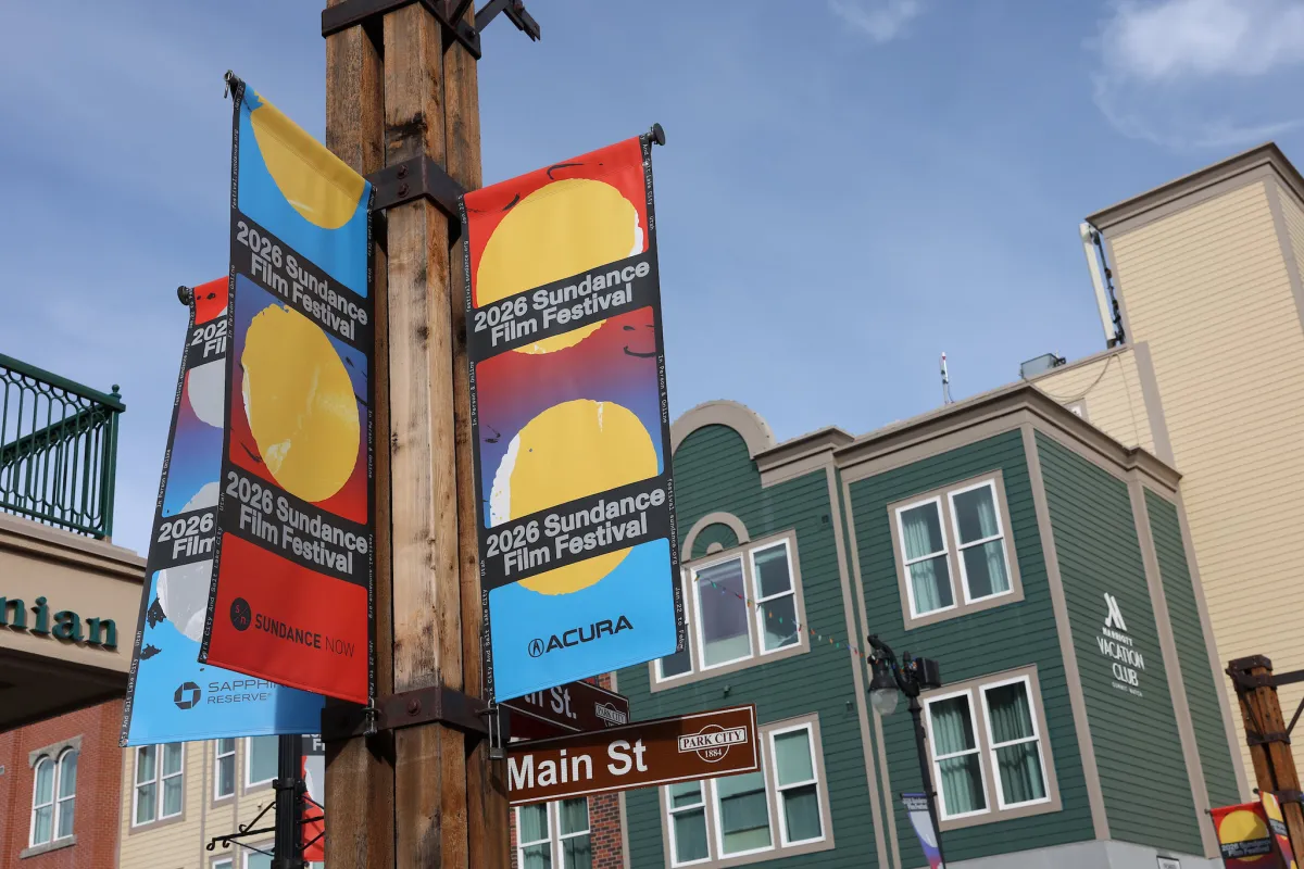 Street lamp posters advertising the 2026 Sundance Film Festival with a view of Main Street buildings against a bright blue sky