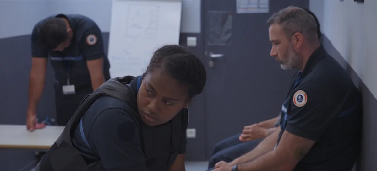 Four uniformed guards appear to wait in a sterile room