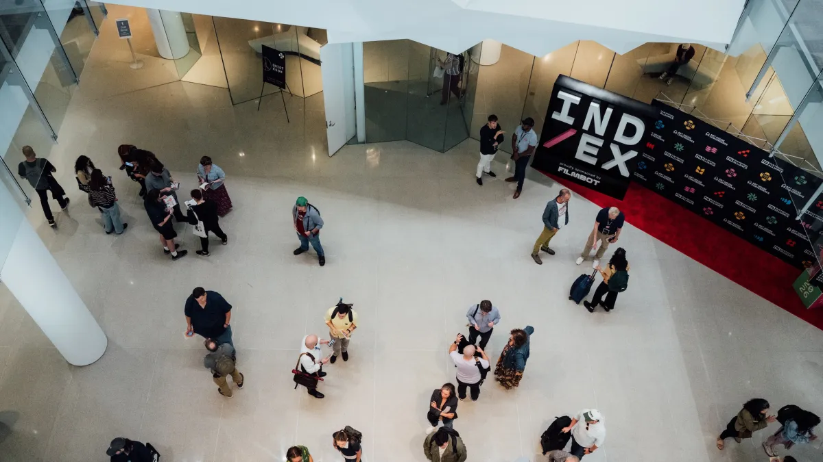 Bird's eye view of a gathering of folks with a step-and-repeat branded as IND/EX seen in the background