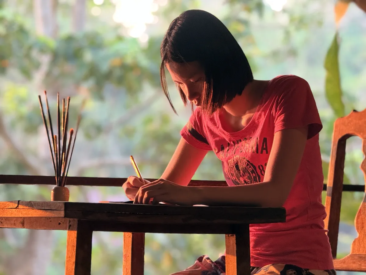 Teenage girl sits at table making art