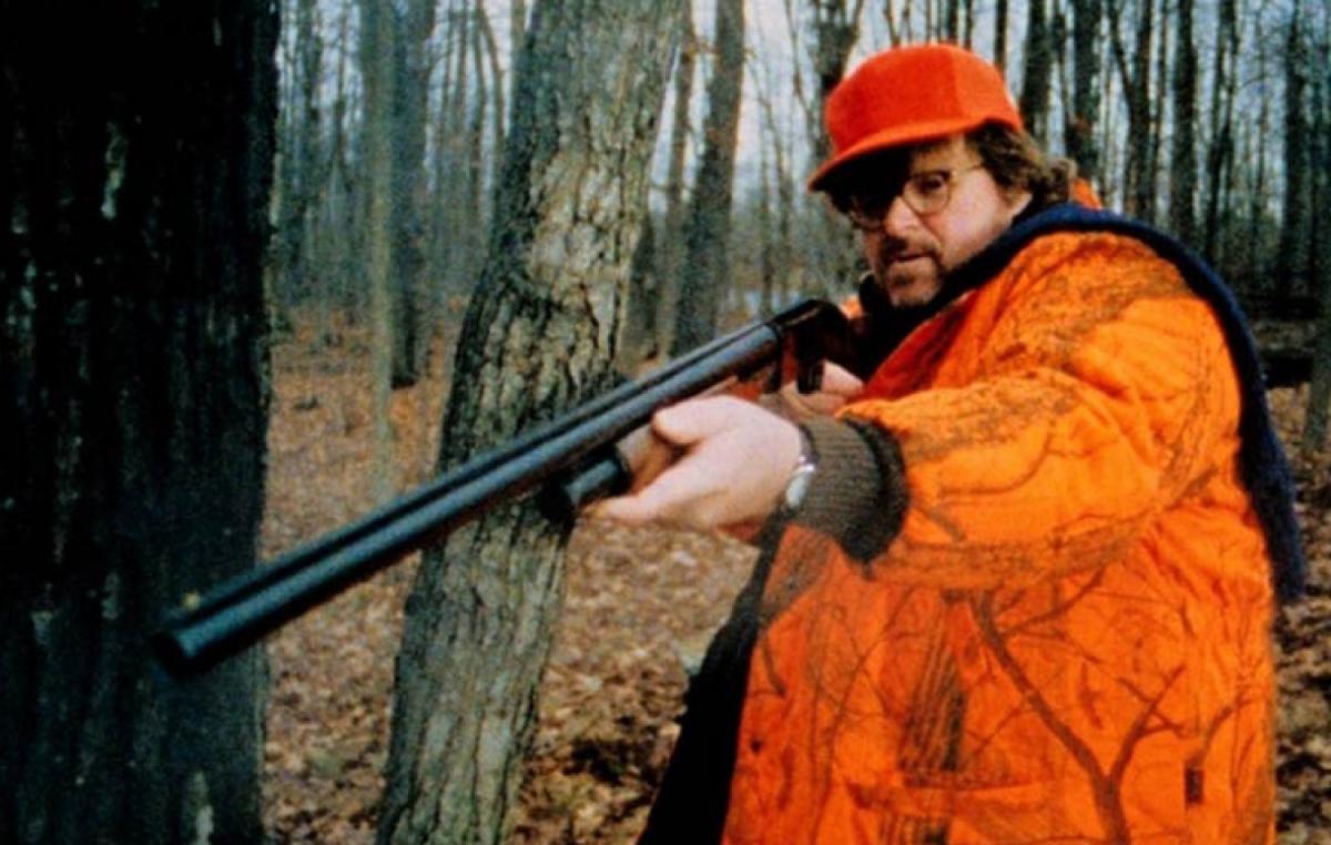 Michael Moore in orange, holding a rifle
