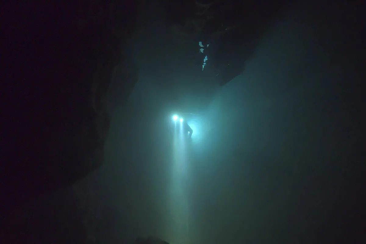 A cave diver, wearing diving equipment and two headlamps, searches in a flooded cave in Thailand for 12 boys and their soccer coach.  From  E. Chai Vasarhelyi and Jimmy Chin's 'The Rescue'  Photo: : National Geographic)