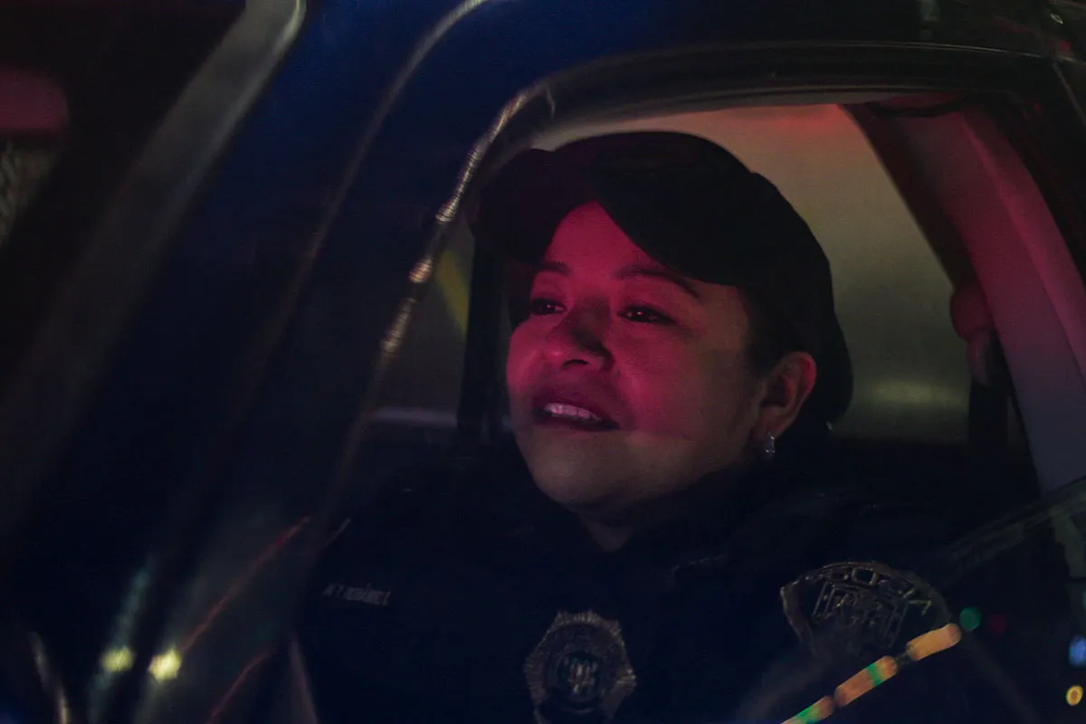 Monica Del Carmen is a Mexican woman dressed as a cop sitting in a police car. From Alonso Ruizpalacios’ ‘A Cop Movie.’ Courtesy of Netflix.