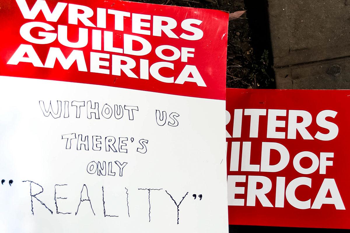 A collection of signs that state “Writers Guild of America: Without Us, There’s Only Reality.” Courtesy of Shutterstock