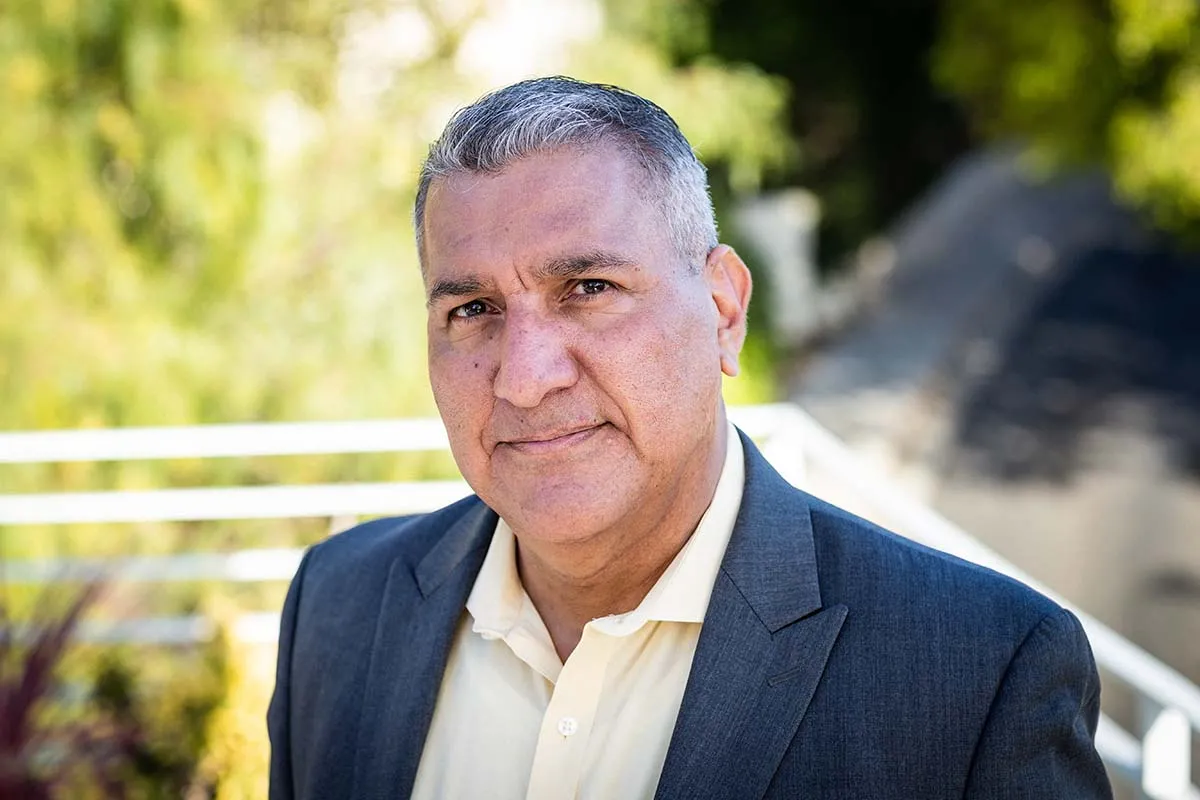 Headshot of IDA Executive Director Rick Perez, a Latinx man with short back and grey hair, standing outside. 