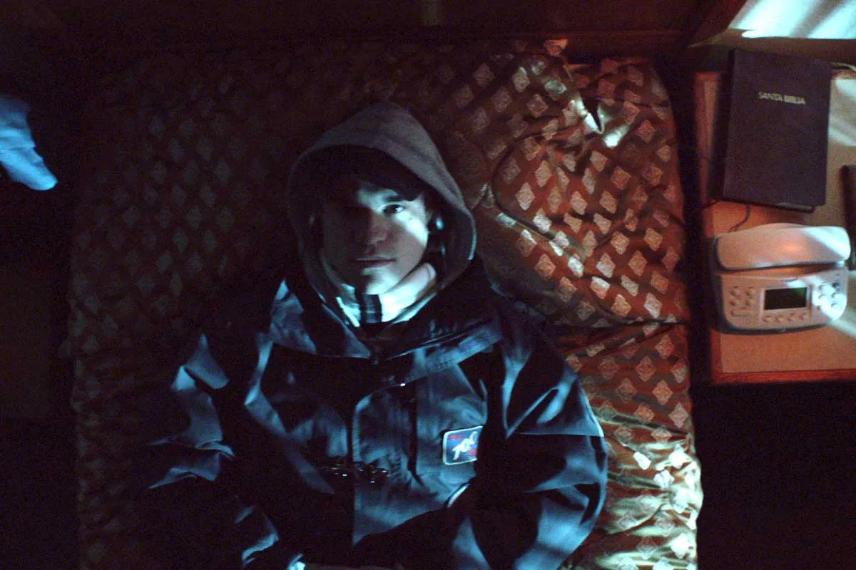 Welsh actor Adam O'Brian is a white male lying on a bed, wearing a hooded jacket—playing Fredric Bourdin. From Bart Layton’s ‘The Imposter.’ Photo by Erik Wilson. 