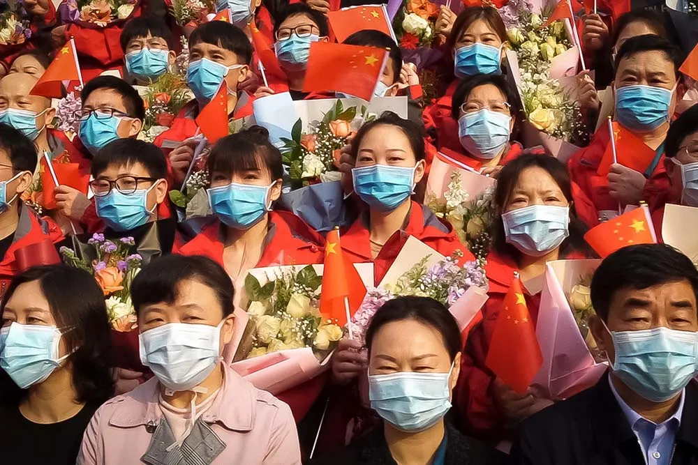 A group of people all wearing face masks waving the Chinese flag.