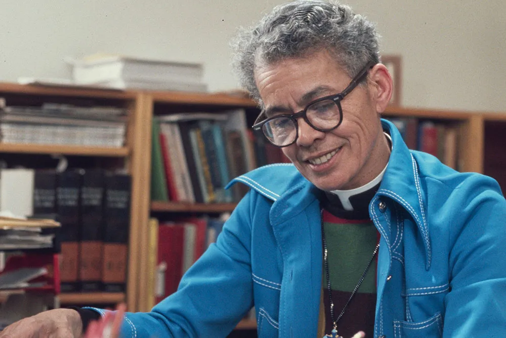 A older Black person with gray hair wearing a blue coat.