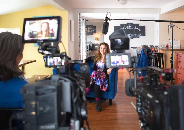 Woman in a galaxy-themed dress sits in an interview set up before a documentary crew