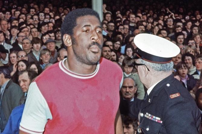 Clyde Best walks through the pitch at West Ham United, with a sea of fans in the stands behind him