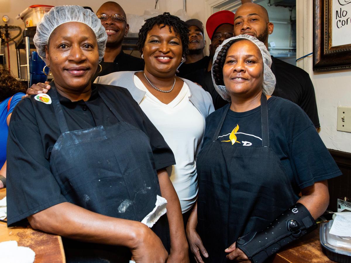 Group of African-American is smiling at the camera in a kitchen.