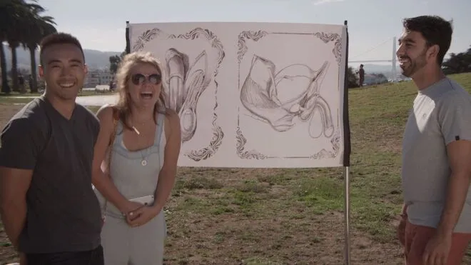 Three people standing in front of a drawing of human genetalia.