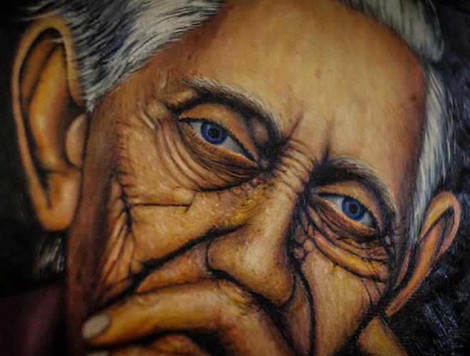 A close-up of a painting of a wrinkled face of an old woman.