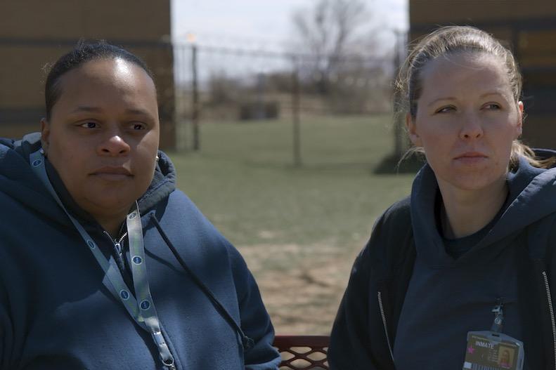 two incarcerated woman sitting on a bench