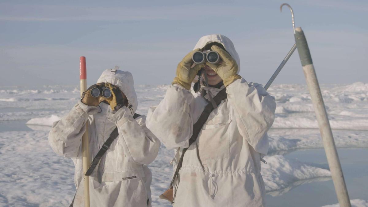 Young hunters in Alaska scan an icy horizon with binoculars. 