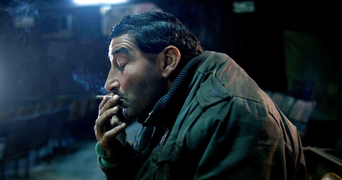 A man smokes in a darkened screening room