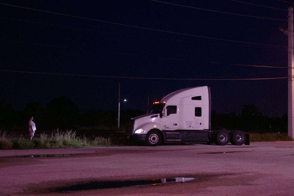 still of female truck driver starring at their truck in the middle of the night