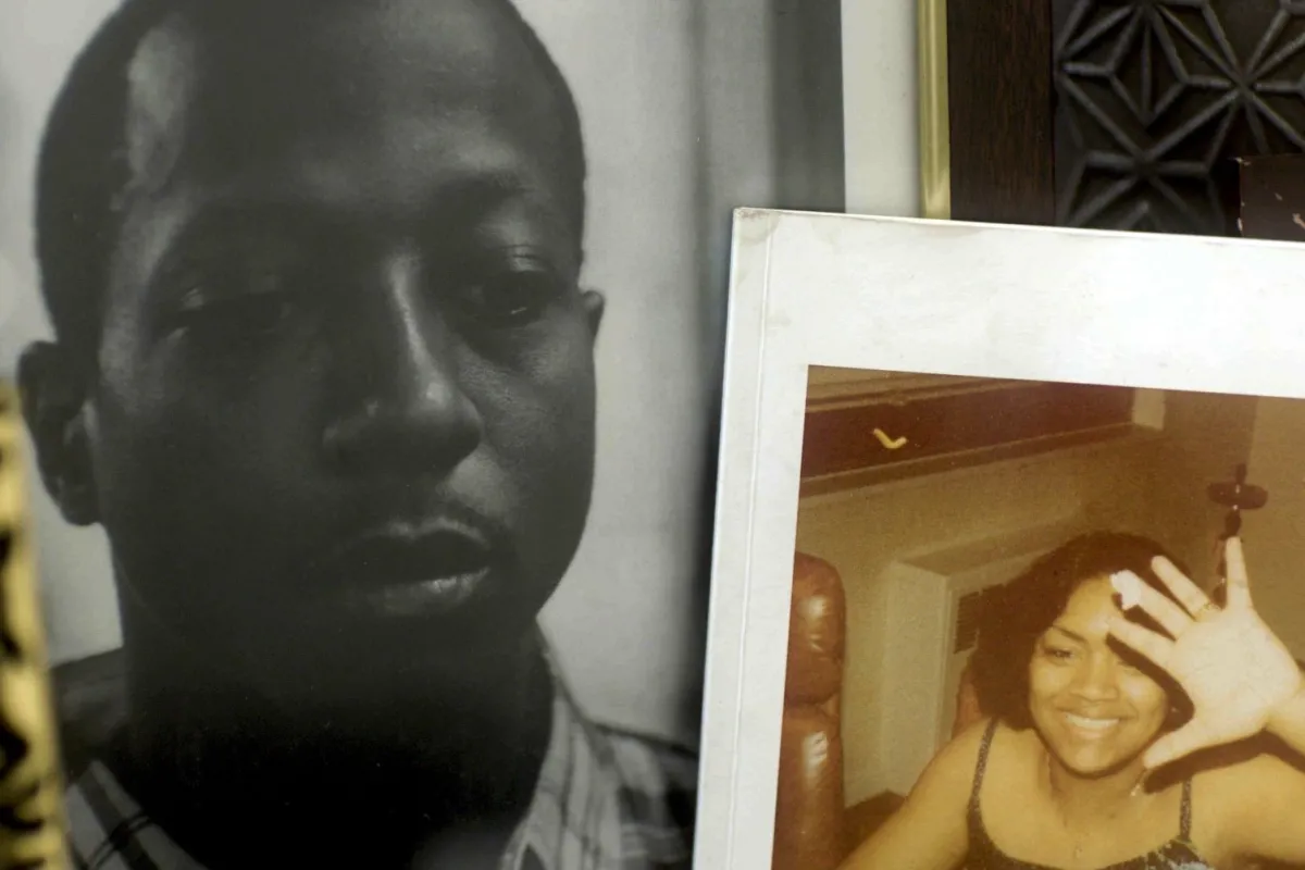 A still from "For Venida, For Kalief": Two framed photos sit on a bedside cabinet, one of Kalief Browder, a young Black man wearing a checked shirt, and the other of a young Black woman wearing a sleeveless black top. 