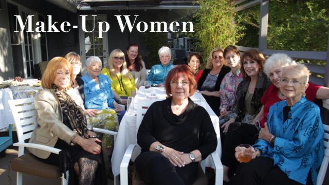 Thirteen elderly White  women sit around a white patio table facing the camera. 