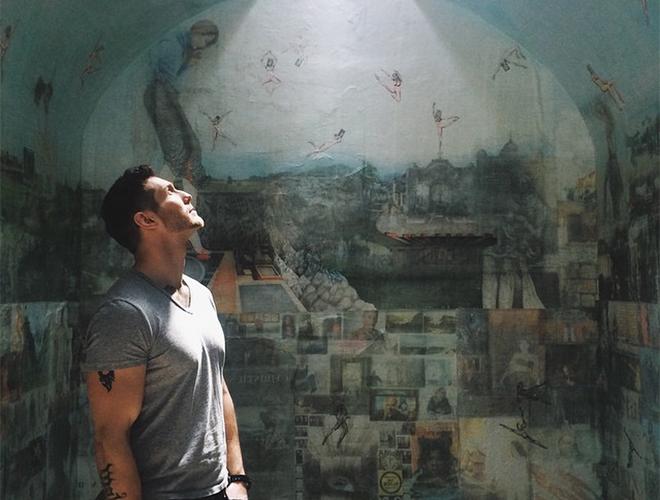 A man is looking up in front of a wall painting.