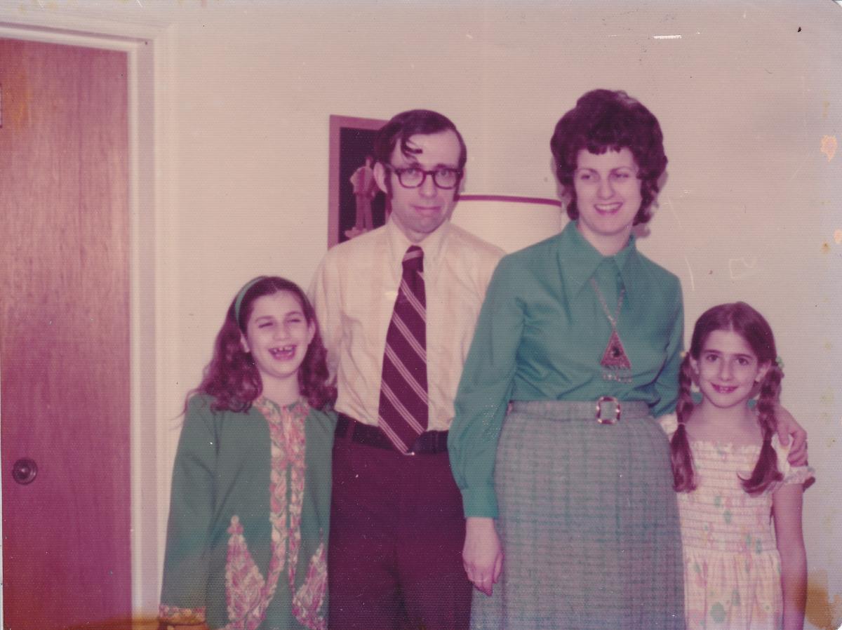A late-20th century family photo with Mom and Dad in the middle and two daughters on either side. 