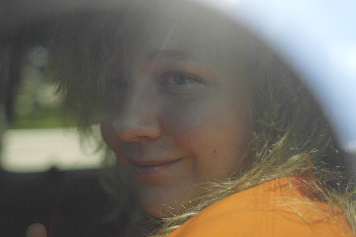 NSA Contractor sits in an orange jumpsuit in the back of a car.