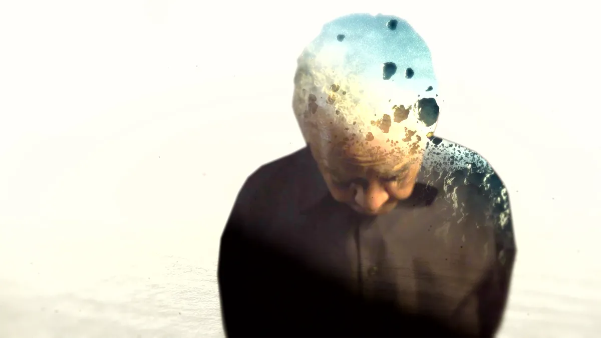 a Black adult in brown shirt looking down